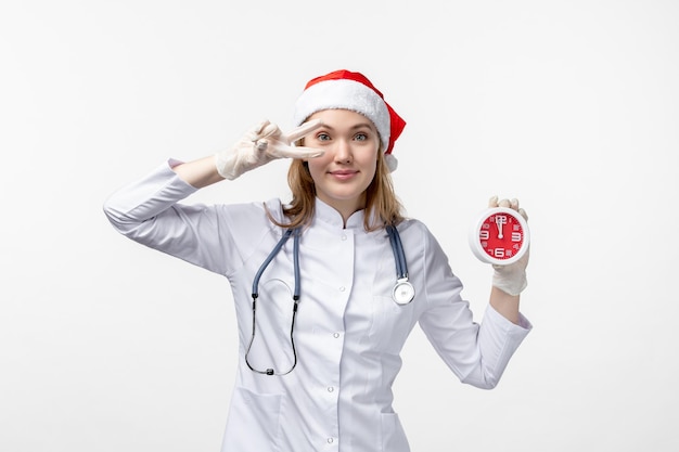 Foto gratuita vista frontale della dottoressa sorridente che tiene l'orologio sul muro bianco