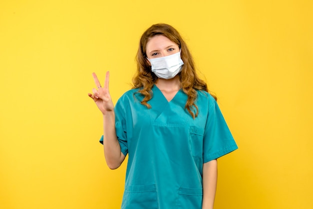 노란색 공간에 마스크에 웃는 전면보기 여성 의사