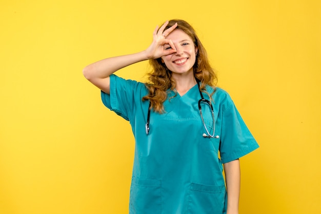 Foto gratuita medico femminile di vista frontale che sorride sullo spazio giallo