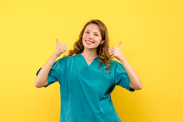 Front view of female doctor smiling on the yellow wall