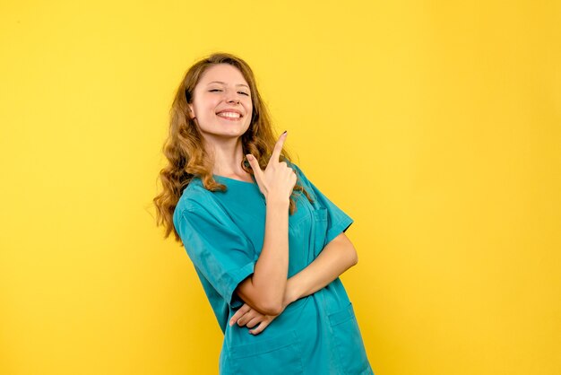 Front view of female doctor smiling on yellow wall