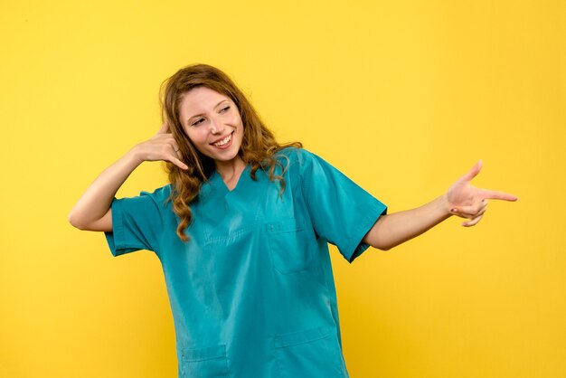 Вид спереди женщины-врача, улыбаясь на желтой стене