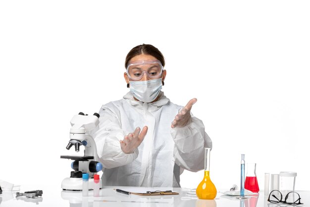 Front view female doctor in special suit and wearing mask on light white background covid- virus pandemic coronavirus