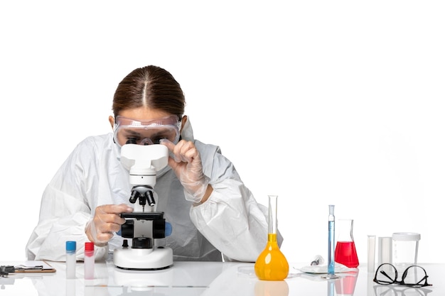 특수 양복과 흰색 책상에 현미경으로 작업하는 마스크 착용 전면보기 여성 의사 covid virus pandemic coronavirus