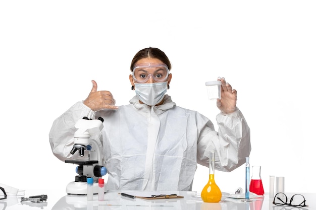 Front view female doctor in special suit and with mask holding empty flask on white background covid- pandemic coronavirus virus health