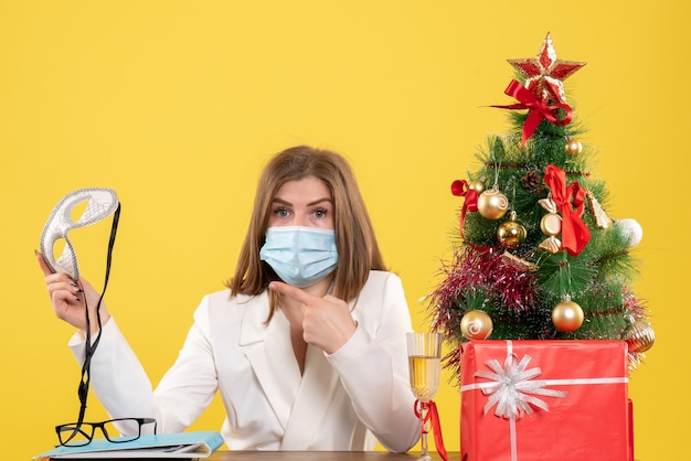 Medico femminile di vista frontale nella maschera sterile che tiene la maschera del partito