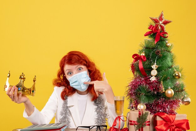 Front view female doctor in sterile mask with crown in her hands