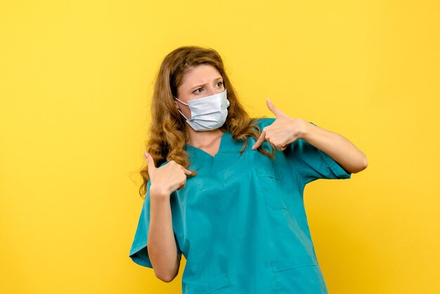 Front view of female doctor in sterile mask on the yellow wall