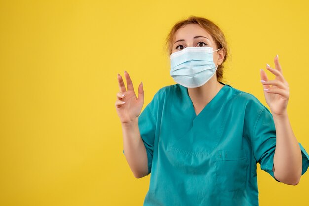 Front view of female doctor in sterile protective mask on a yellow wall