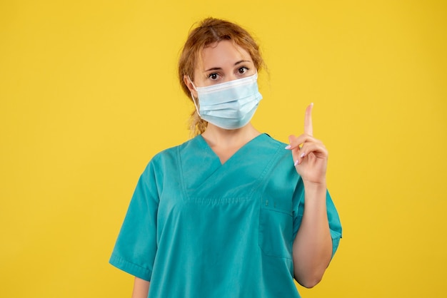 Front view of female doctor in sterile protective mask on a yellow wall