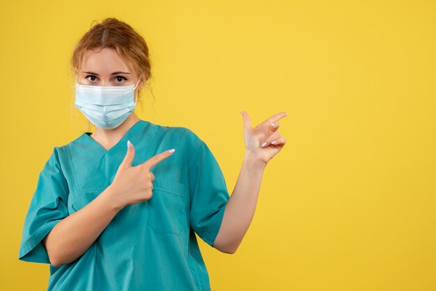 Front view of female doctor in sterile protective mask on yellow wall