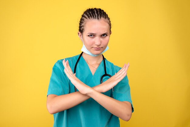 Front view of female doctor in sterile protective mask on yellow wall