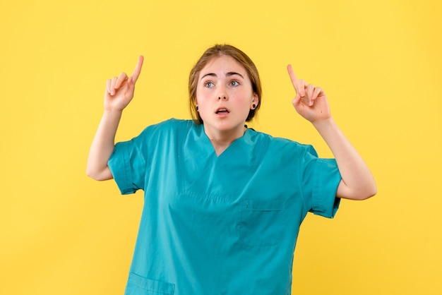 黄色の背景の感情病院の健康医学を考えている正面図の女性医師