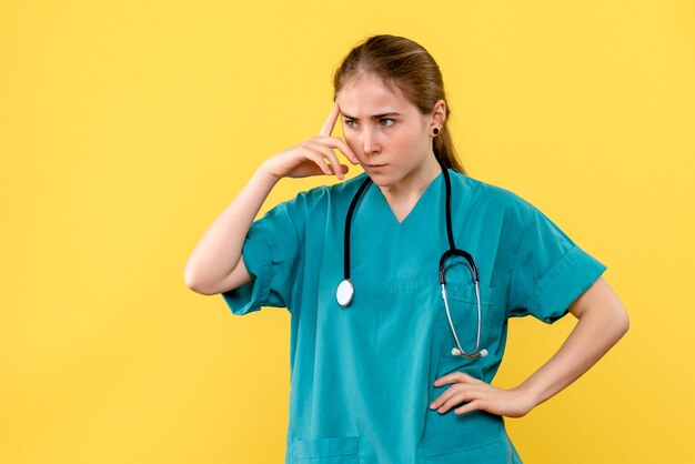 Front view female doctor thinking on a yellow background medic hospital health emotion