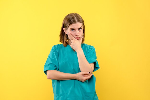 Front view female doctor thinking on yellow space