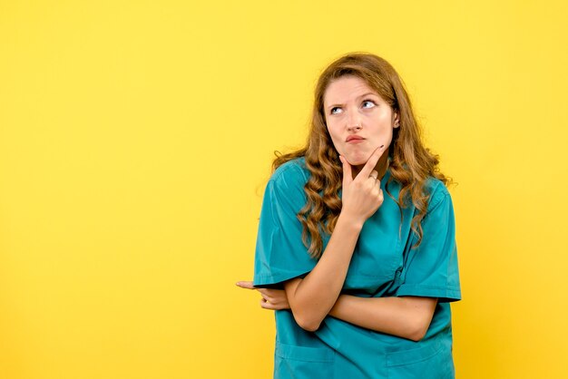 Front view of female doctor thinking on yellow wall