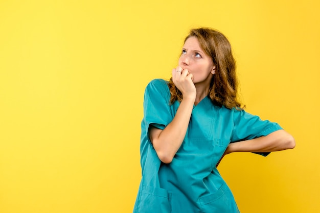 Front view of female doctor thinking on yellow wall