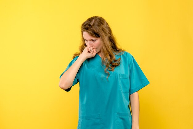 Front view of female doctor thinking on yellow wall