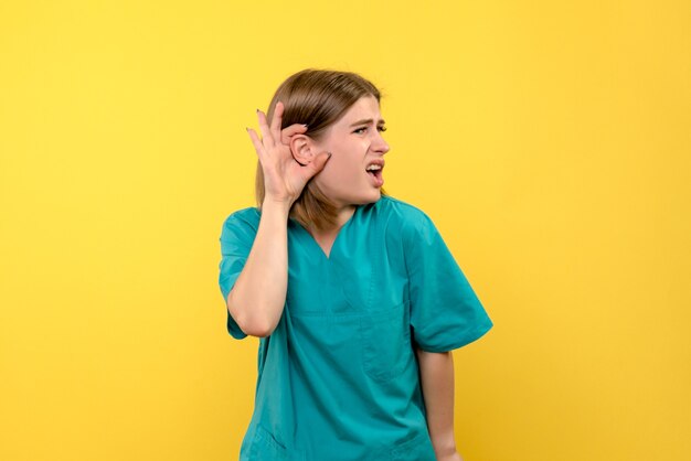 Front view female doctor trying to listen on yellow space