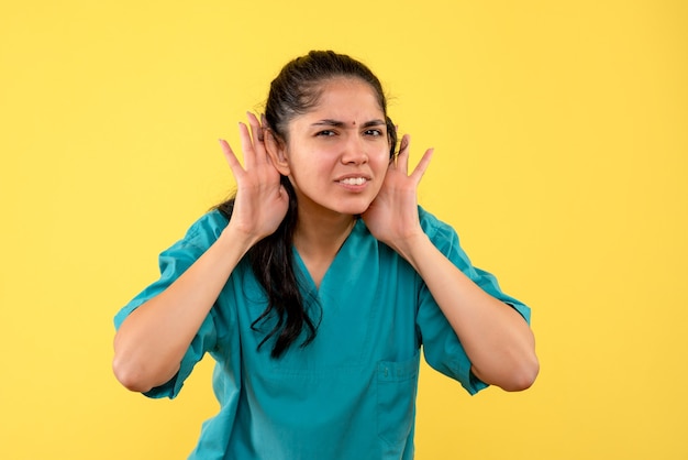 Foto gratuita medico femminile di vista frontale in uniforme che mette le mani vicino alle sue orecchie in piedi