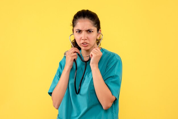 Front view female doctor using stethoscope standing