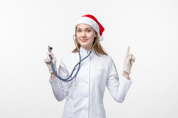 Front view of female doctor using stethoscope on the white wall
