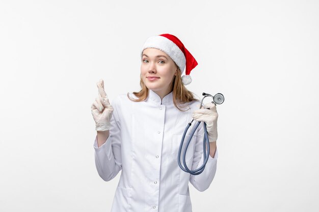 Front view of female doctor using stethoscope on white wall