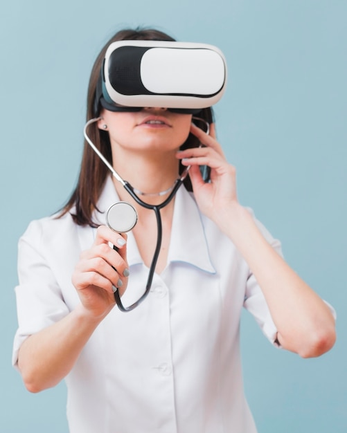 Вид спереди женщина-врач с помощью виртуальной реальности гарнитуры и стетоскопа