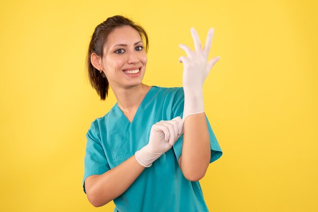 Front view female doctor wearing gloves on yellow background