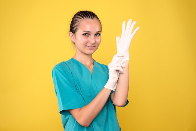 Front view of female doctor wearing gloves on yellow wall