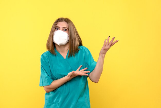 Front view female doctor wearing mask on a yellow space