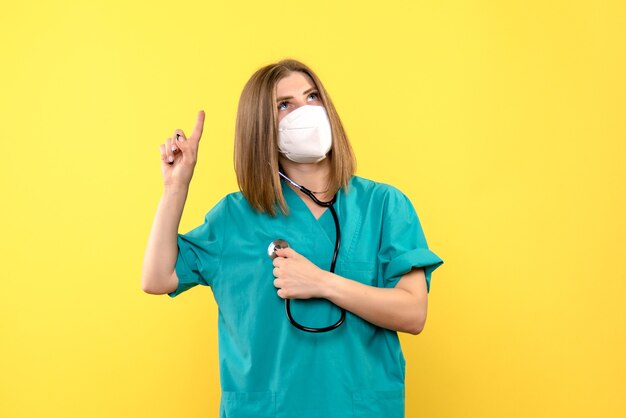 Front view female doctor wearing mask on a yellow space