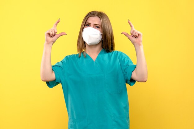 黄色いスペースにマスクを身に着けている正面図の女性医師