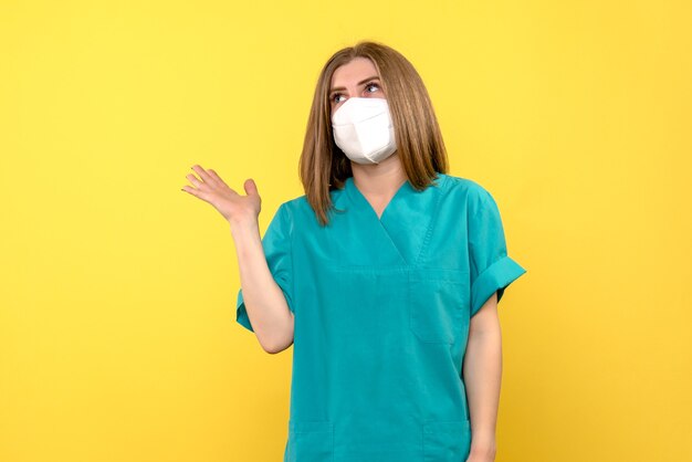 Front view female doctor wearing mask on yellow space