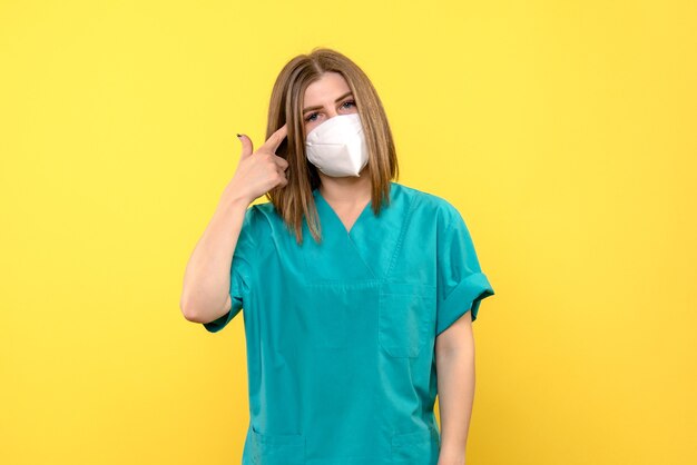 Front view female doctor wearing mask on yellow space