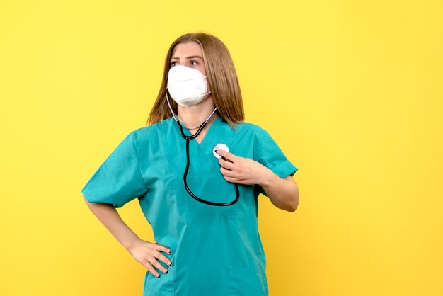 Front view female doctor wearing sterile mask on yellow space