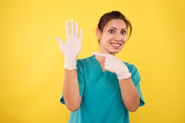 Front view female doctor in white gloves on yellow background