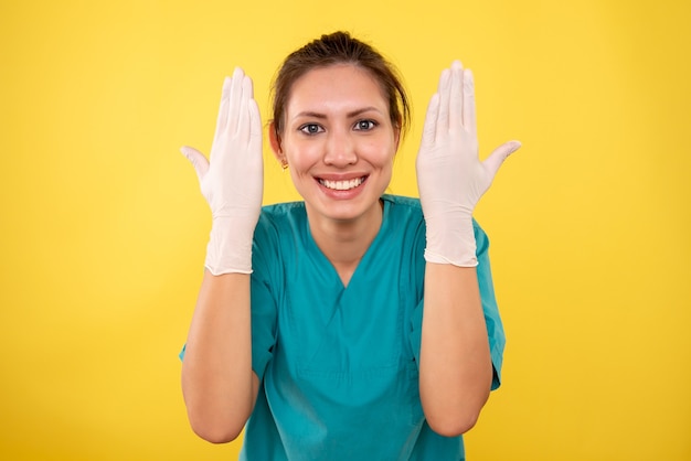 Front view female doctor in white gloves on yellow background