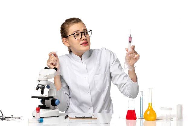 Front view female doctor in white medical suit holding injection on a white space