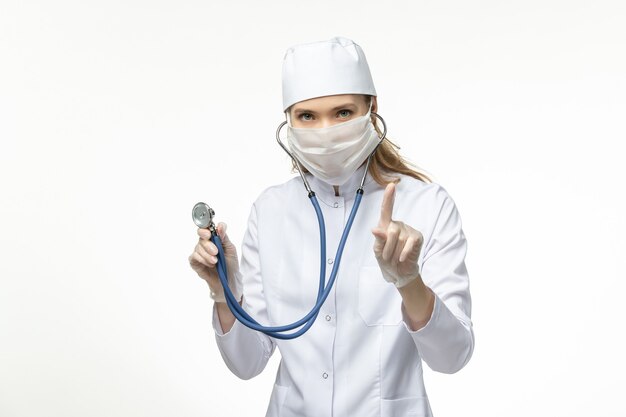 흰색 책상 질병 코로나 바이러스로부터 보호하기 위해 흰색 의료 복과 마스크의 전면보기 여성 의사