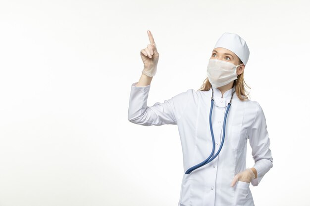 흰 벽에 코로나 바이러스로부터 보호하기 위해 흰색 의료 복과 마스크의 전면보기 여성 의사 covid- pandemic
