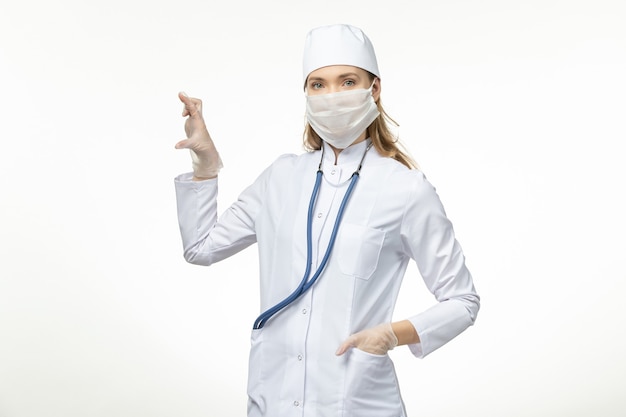 白い壁の病気の共同流行のコロナウイルスからの保護として白い医療スーツとマスクの正面図の女性医師