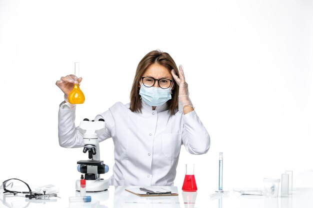 밝은 공백에 대한 솔루션으로 작업하는 코로나 바이러스로 인해 흰색 의료 복 및 마스크의 전면보기 여성 의사
