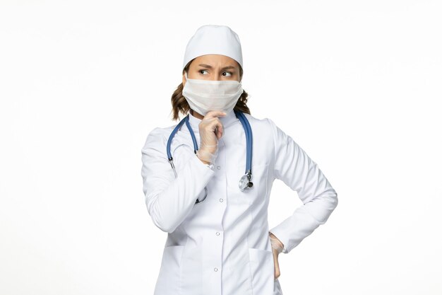 Вид спереди женщина-врач в белом медицинском костюме и маске, думающая на белой стене, медицина болезни, вируса пандемии