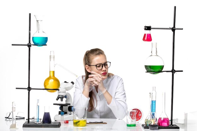 흰색 배경 covid 유행성 화학 바이러스에 대한 솔루션 테이블 앞에 앉아 흰색 의료 소송에서 전면보기 여성 의사