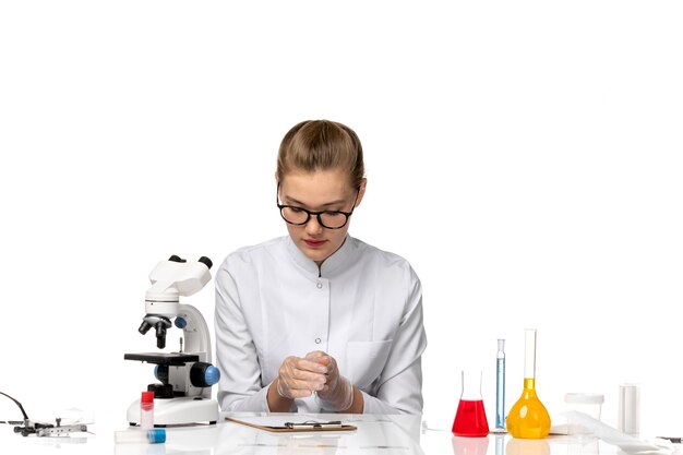 Front view female doctor in white medical suit sitting on white space