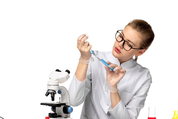 Front view female doctor in white medical suit with gloves working with solutions on white space