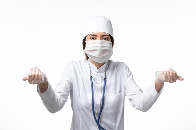 밝은 흰 벽에 코로나 바이러스로 인해 마스크가있는 흰색 의료 소송에서 전면보기 여성 의사 질병 의학 바이러스 대유행 covid-