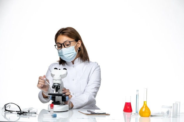 Free photo front view female doctor in white medical suit with mask due to covid working on a white space