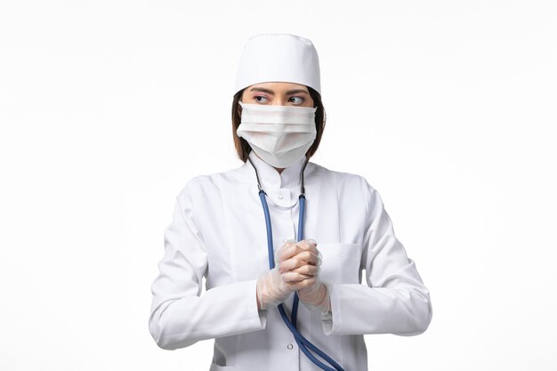 Front view female doctor in white medical suit with a mask due to pandemic on white desk disease medicine virus pandemic covid-